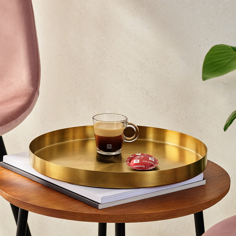 Cápsula de café Nespresso y espresso sobre una bandeja dorada